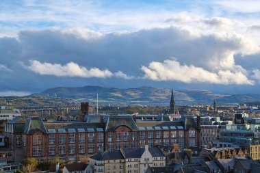 Edinburgh, İskoçya, 29 Mart 2025: Edinburgh 'un tarihi binalarını dramatik bir siluete karşı gösteren geniş bir görüntüsü. Yuvarlanan tepeler ve canlı bir gökyüzü şehrin mimari cazibesiyle doğal güzellikleri harmanlayan çarpıcı bir zemin oluşturur..