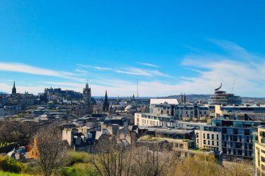 Edinburgh, İskoçya, 1 Nisan 2025: Edinburgh 'un canlı şehir manzarası parlak mavi gökyüzü altında tarihi ve modern mimarinin bir karışımını sergiliyor. Belirgin işaretler ve şehir yeşilliği olay yerine derinlik katarak şehrin cazibesini ve karakteristik özelliklerini yansıtıyor.