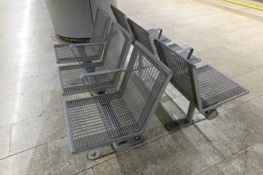 Metal ağ koltukları çağdaş bir metro istasyonunda, şehir sakinleri için minimalist bir tasarım sunarak hizalanır. Endüstriyel estetik geniş, temiz platformu tamamlar, toplu taşıma ortamlarında verimliliği ve modernliği artırır.