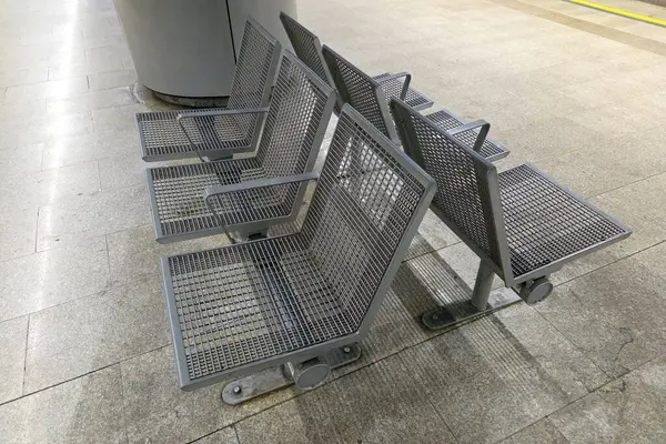 Metal ağ koltukları çağdaş bir metro istasyonunda, şehir sakinleri için minimalist bir tasarım sunarak hizalanır. Endüstriyel estetik geniş, temiz platformu tamamlar, toplu taşıma ortamlarında verimliliği ve modernliği artırır.
