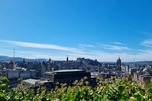 Edinburgh, İskoçya, 1 Nisan 2025: Edinburgh 'un şehir manzarası, canlı mavi gökyüzü altında tarihi mimarisini ve ikonik kalesini sergiliyor. Panoramik manzara, doğal manzara ve s ile çevrili antik ve modern yapıların karışımını vurgular.