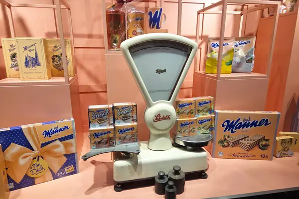 Viyana, Avusturya, 3 Mayıs 2025: Şeftali rengi arka planda çeşitli şekillerde gofret kutularıyla çevrili klasik bir tartı. Vitrin nostaljik bir cazibe yayıyor, markanın retro ambalaj tasarımı..