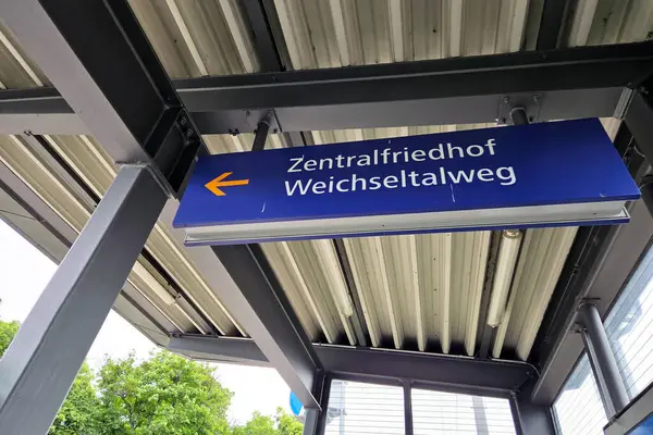 Viyana, Avusturya, 4 Mayıs 2025: Zentralfriedhof weichseltalweg için açık hava tren istasyonu tabelası bir metal çerçevede sergilenmektedir. İşaret, yeşillik ve endüstriyel mimari unsurların çerçevelediği yönü gösteren bir ok içeriyor..