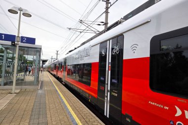 Viyana, Avusturya, 4 Mayıs 2025: Wi-fi ve bisiklet deposu gibi konforlara sahip bir Avrupa demiryolu platformunda lüks bir tren. Canlı kırmızı ve beyaz tasarım, çevre dostu iletişim için verimli bir seyahat sağlayarak modernliğini vurguluyor.
