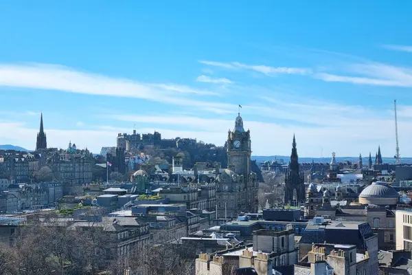 Edinburgh, İskoçya, 1 Nisan 2025: Edinburgh 'un tarihi ufuk çizgisinin panoramik görüntüsü parlak mavi gökyüzünün altındaki ikonik kale ve saat kulesini gösteriyor. Sahne şehrinin mimari cazibesi ve seyahat tasarımları için ideal bir zemin görevi görüyor..