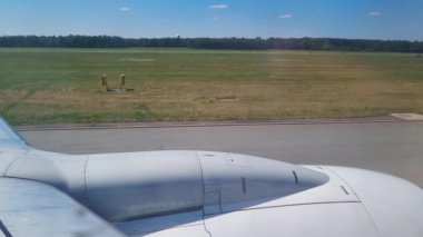 Piste bakan uçak kanadı ve açık havada yeşillik manzarası