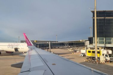 Barcelona, Spain, January 4, 2025: View from an airplane window capturing an airport terminal with a wing in the foreground. a passenger aircraft is parked on the tarmac, with terminal buildings and jet bridges visible. the serene morning light adds 