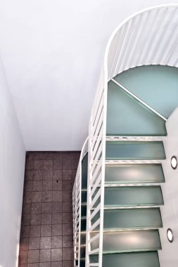 Minimalist mimari sergilenen modern bir merdiven kıvrımlı bir tasarım ve nane yeşili basamaklar içerir. Temiz beyaz duvarlar ve fayanslarla çevrili olan bina, çağdaş iç tasarım estetiğini ön plana çıkarıyor..