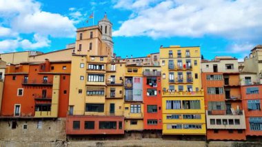 Girona, İspanya, 3 Ekim 2024: Canlı, çok renkli binalar girona, İspanya 'da nehir boyunca uzanır ve çarpıcı bir mimari çeşitlilik sergilerler. Açık mavi gökyüzü ile tezat oluşturan parlak cepheler, güzel ve davetkar bir sahne yaratıyor.