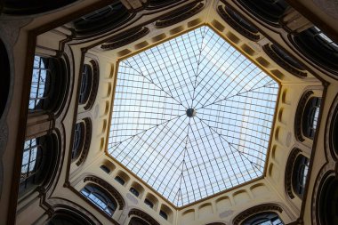 Viyana, Avusturya, 3 Mayıs 2025: Simetrik cam kubbeye baktığımızda, bu iç görünüş, tarihi bir binanın avlusuna doğal ışık saçan karmaşık desenler ve merkezi bir tavan penceresi içeren klasik bir mimari tasarım sergiliyor..