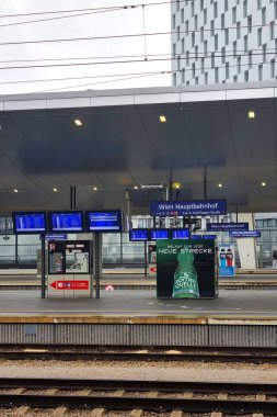 Viyana, Avusturya, 5 Mayıs 2025: Birden fazla elektronik zaman çizelgesi, büyük bir seyahat reklamı ve istasyonun modern mimarisini gösteren Viyana hauptbahnhhhhhof manzarası. Tren rayları ön planda, kentsel binaların arka planıyla görülebilir..