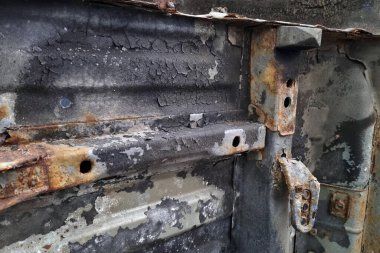 Yıpranmış bir endüstriyel metal yüzeye yakın çekim. Pas, soyulmuş boya ve aşınma var. özellikler, sert, ham estetiğe eklenen delikler ve cıvatalarla, doku ve renklerin bir yamasını içerir..