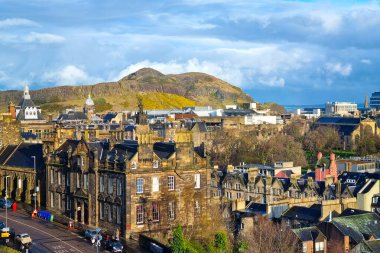 Edinburgh, İskoçya, 29 Mart 2025: Edinburgh 'un tarihi mimarisi doğal güzellikle harmanlanır, Arthur' un arka planına karşı karmaşık çatılar sergilenir. Manzara, canlı bir gökyüzü altında kentsel ve doğal elementleri birleştirir..