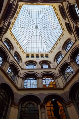 Viyana, Avusturya, 3 Mayıs 2025: Geometrik cam tavanlı tarihi bir avlunun çarpıcı manzarası. Karmaşık mimari detaylar ve simetrik tasarım klasik iç mekanların takdir edilmesini sağlıyor. Işık ve gölge oyunları güçlendirir.
