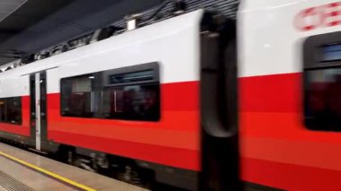 Viyana, Avusturya, 4 Mayıs 2025: Gösterişli, modern bir istasyon platformundan ayrılırken kırmızı ve beyaz dış görünüşüyle karakterize edilen yüksek hızlı bir trenin yer aldığı dinamik bir sahne. resim seyahat temalarını iletir