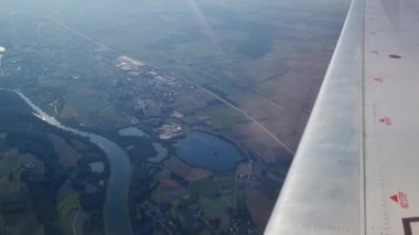 Nefes kesici bir hava manzarası, kıvrımlı bir nehir, yama alanları ve küçük bir kasabanın yer aldığı geniş bir araziyi ortaya çıkarır. Uçak kanadı bir seyahat ve keşif unsuru, aşağıdaki arazinin güzelliği ve enginliği ekler..