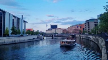 Berlin, Almanya, 24 Mayıs 2025: Berlin 'de sakin bir nehir gezisinin akşam manzarası, ikonik televizyon kulesini modern mimarinin bir zeminine ve sakin bir gökyüzüne karşı sergiliyor. Seyahat ve turizm tasarımı için ideal şehir cazibesi ve mimari