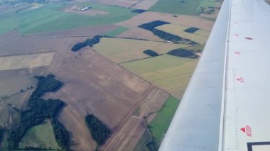 Kırsal alanlara geniş hava manzarası farklı büyüme aşamalarında çeşitli tarlalar gösteriyor. Uçak kanadı aşağıda seyahat ve macera hissi, manzara kalıpları ve tarımsal çeşitlilik sağlar.
