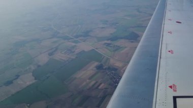 Hava perspektifi, uçuş sırasında bir uçaktan görülen tarımsal alanların bir kısmını gösteriyor. Sahne tarım arazisi geometrisini vurguluyor, yollar ve dağınık binalar manzaraya derinlik katıyor.