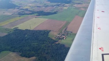Hava perspektifi uçağın kanadının altında geniş tarım arazileri ve yemyeşil alanlar, ekili alanlarla doğal manzaralar arasındaki zıtlık, seyahat ve doğa temaları için idealdir..