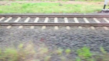 Hareket halindeki tren raylarının dinamik görüntüsü hız ve yolculuğun özünü yakalıyor. Sahne yemyeşil çimenler ve çakıllar içeriyor, kırsal kesimde bir yolculuğu yansıtıyor..