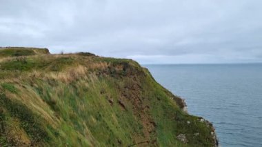 Bereketli yeşilliklerle bezenmiş nefes kesici bir kıyı kayalığı bulutlu bir gökyüzünün altında ufka doğru uzanıyor. Sakin okyanusun geniş manzarası engebeli doğal manzarayı tamamlıyor. Barış ve özgürlük duygusunu çağrıştırıyor..