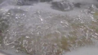 Kaynar suyun yükselen buhar ve dans eden baloncuklarla yakın çekim görüntüsü, sıcaklığın dinamik enerjisini gösteriyor. Mutfak ortamında pişirme, ısıtma ve aşçılık hazırlama süreçlerini temsil etmek için ideal..