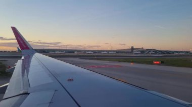 Barselona, İspanya, 4 Ocak 2025: Havaalanı pistinin üzerindeki sakin bir uçak penceresinden manzaralı bir manzara, seyahat ve havacılığın güzelliğini gösteriyor. Gökyüzünün yumuşak renkleri kanat ve asfaltın endüstriyel çizgileriyle tezat oluşturuyor..