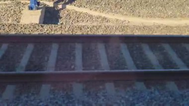 Etrafı çakıl ve endüstriyel elementlerle çevrili demiryolu rayları. Bu ulaşım altyapısının özü, dayanıklılığı vurgulamak ve tren rayları ve demiryolu ortamlarının tipik engebeli estetiği.