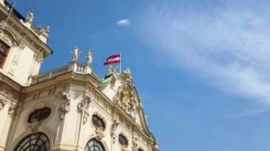 Vienna, Austria, May 3, 2025: Ornate architectural elements of belvedere palace in vienna, austria, are highlighted against a bright blue sky. the austrian flag waves proudly, symbolizing national heritage and european history.
