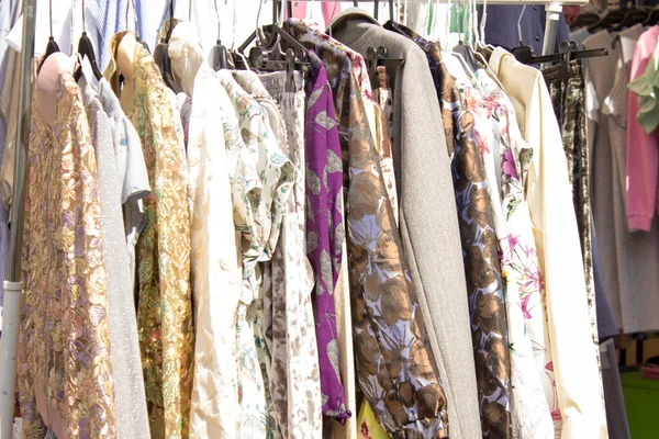Askıda elbiseler, parlak kadın kıyafetleri. Panayırda elbiseler.