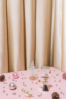 Altın saten perdeli eski moda Noel konsepti ve pembe masanın köşesinde mücevher ve melek süsleri, hediye kutuları ve çam kozalakları. Vertican kış tatil sezonu kartı. 