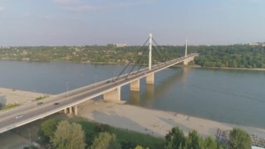 Nehir manzaralı bir köprü beton ağaçlar trafiği. Hava aracı görüntüsü. Kamera alacakaranlıkta bir nehrin üzerinde asılı duran beton köprüye doğru uçuyor..