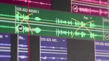 Ses düzenleme programı çoklu oturum dalga şeklinde çalışıyor. Bilgisayar ekranı. Ses düzenleyici mühendisi çalışıyor. Ses düzenleme yazılımındaki bir bilgisayar ekranının Dolly izleme görüntüsü. Alçak alan derinliği.
