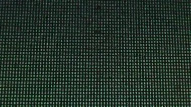 Siyah ekrandaki kod değişimlerini listeleyen numaralar rastgele hareket eden yeşil kamera bir bilgisayar ekranından geçiyor. Bilgisayar ekranında bir sayı matrisi. Siyah arkaplanda yeşil sayılar. Arama veri hatası kodu programlanıyor.