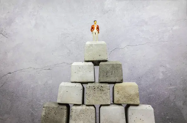 Güç ve güç. Beton blokların üzerinde zafer kazanıldı. Hayat zarif ve şık giyimli. Dünyanın tepesindeyim! Güç ve güç kazanan iş adamı beton blokların üzerinde duruyor. Hayat, zarif ve şık giyimli.
