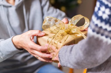 Closeup of hands of senior woman and a child holding a gift at Christmas