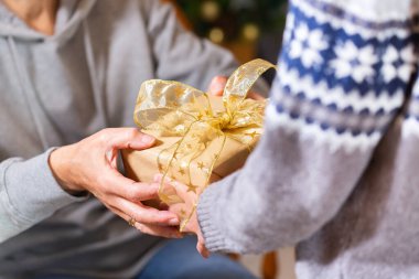 Closeup of hands of senior woman and a child holding a gift at Christmas