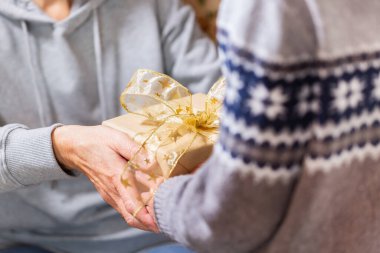 Closeup of hands of senior woman and a child holding a gift at Christmas