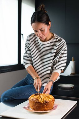 Young beautiful woman cutting homemade apple pie at the modern kitchen