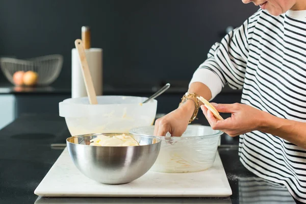 Woman putting apples while cooking apple pie in the modern kitchen