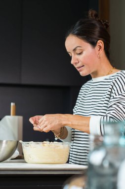 Woman putting apples while cooking apple pie in the modern kitchen