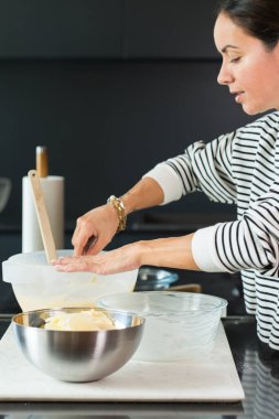Woman putting apples while cooking apple pie in the modern kitchen