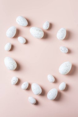 Pembe arka planda altın, beyaz, siyah noktalı ve çizgili yumurtalarla mutlu Paskalya çerçeveleri. Üst görünüm, düz görünüm, kopyalama alanı. Modern Paskalya tebrik kartı