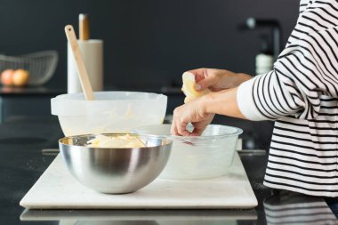 Woman putting apples while cooking apple pie in the modern kitchen