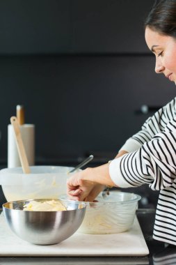 Woman putting apples while cooking apple pie in the modern kitchen