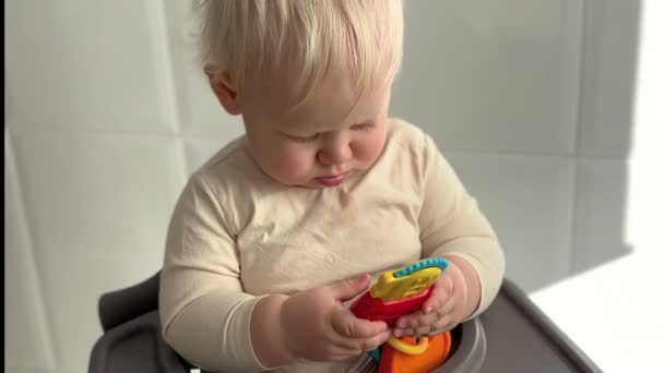 Mały Chłopiec Uśmiecha Się Bawi Zabawką Siedząc Krześle Nagranie Poziome — Wideo stockowe