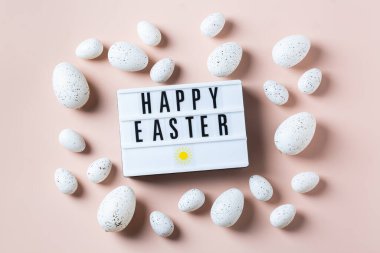 Pembe arka planda altın, beyaz, siyah noktalı ve çizgili yumurtalarla mutlu Paskalya çerçeveleri. Üst manzara, düz yatış. Modern Paskalya tebrik kartı
