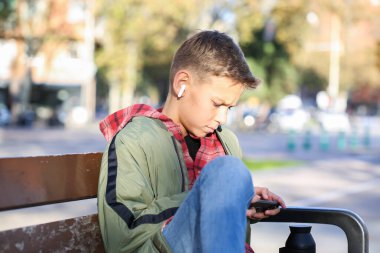 Yakışıklı bir genç telefonuna bakıyor şehir sokaklarında bir bankta oturuyor, açık havada. Kafkas delikanlısı arkadaşlarını yürüyüş için bekliyor.