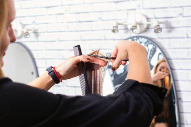 Profesyonel kuaför, müşteri saçını makasla keser ve modern bir kuaförde saçını kestirir. Kuaför, beyaz kadın için özel muamele uyguluyor.